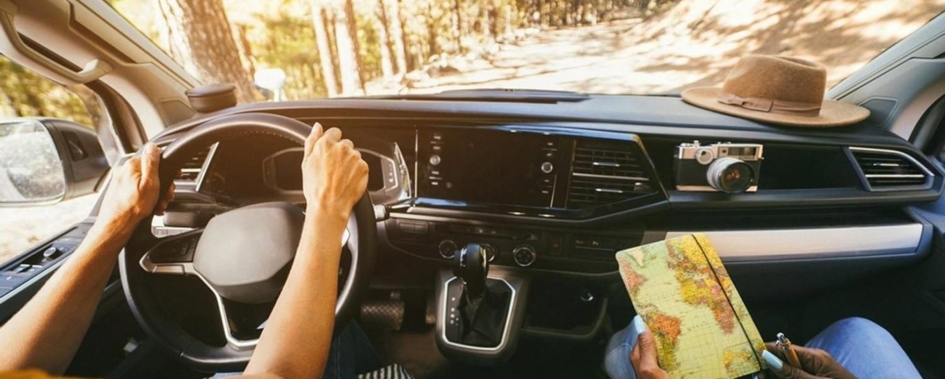 View from inside a crossover on a forest road in Australia with a driver and a passenger holding a map